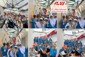 Tour group on a cruise ship posing for a photo in matching blue shirts and hats; Alhijaz Tour & Travel logo visible in the top right corner